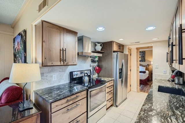 kitchen featuring wall chimney exhaust hood, stainless steel appliances, dark stone counters, sink, and backsplash