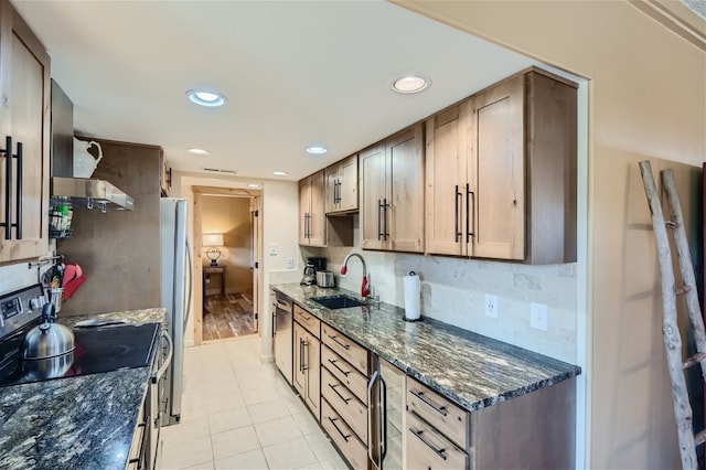 kitchen featuring light tile patterned floors, appliances with stainless steel finishes, tasteful backsplash, wall chimney exhaust hood, and sink