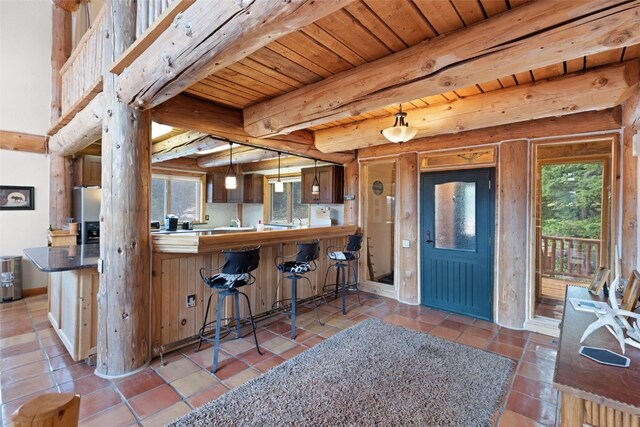 kitchen with wooden ceiling, stainless steel refrigerator with ice dispenser, beamed ceiling, decorative light fixtures, and kitchen peninsula