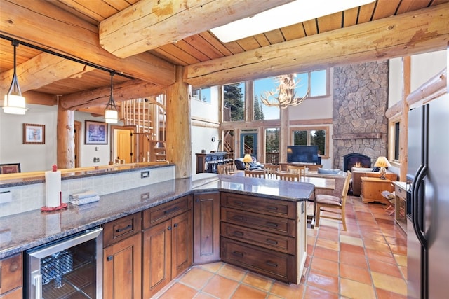 kitchen with a fireplace, pendant lighting, wine cooler, and beamed ceiling