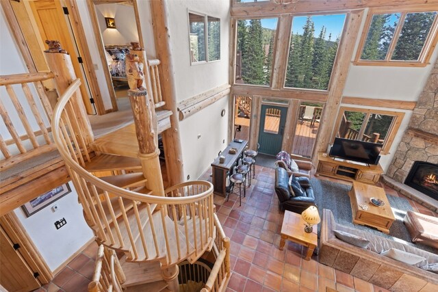 tiled living room featuring a stone fireplace and a towering ceiling