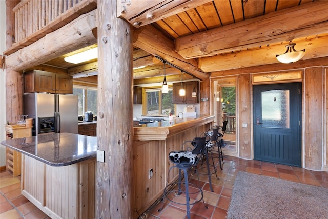 kitchen with beam ceiling, stainless steel fridge with ice dispenser, kitchen peninsula, pendant lighting, and a breakfast bar