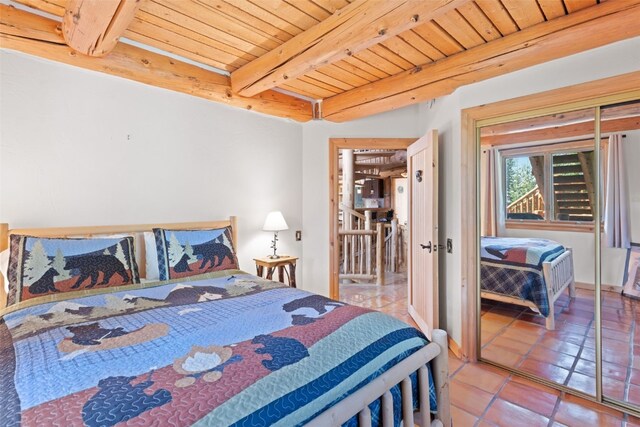 bedroom with beam ceiling, light tile patterned flooring, and wooden ceiling