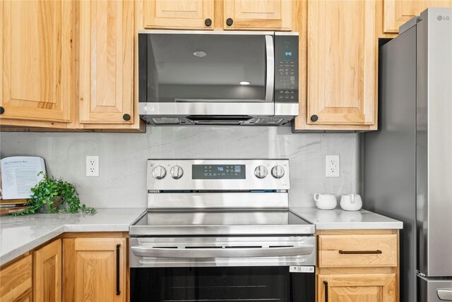 kitchen featuring appliances with stainless steel finishes, light brown cabinets, and tasteful backsplash