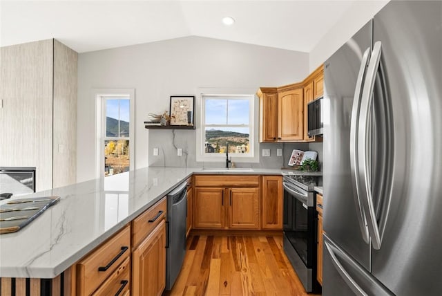 kitchen featuring kitchen peninsula, light stone countertops, sink, and appliances with stainless steel finishes