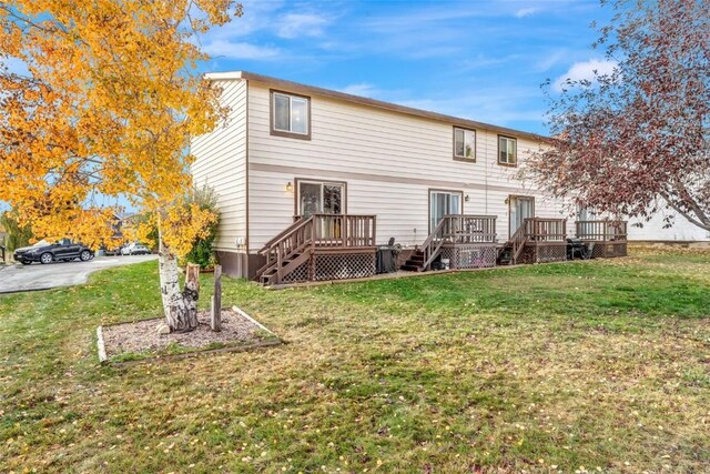 rear view of house with a lawn and a wooden deck