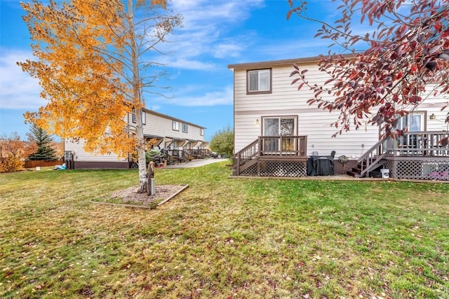 rear view of property featuring a wooden deck and a lawn