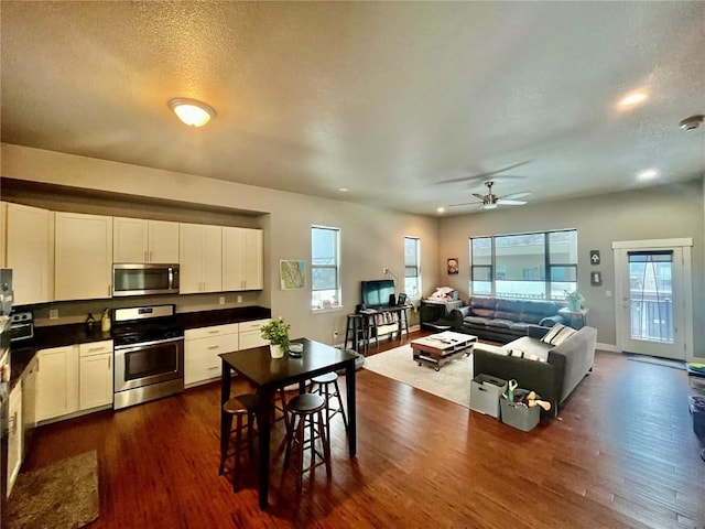 kitchen featuring dark wood finished floors, dark countertops, white cabinetry, and appliances with stainless steel finishes