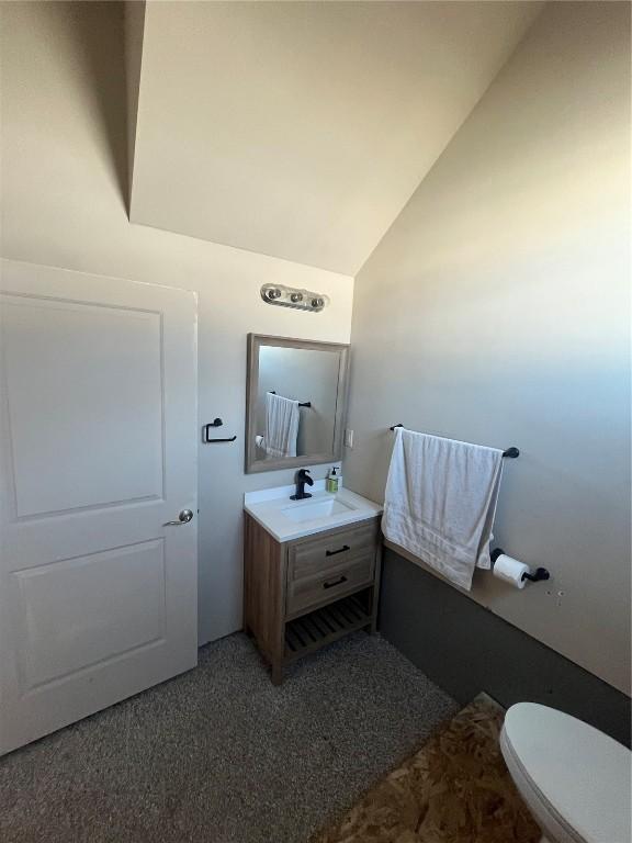 bathroom featuring toilet, vanity, and vaulted ceiling