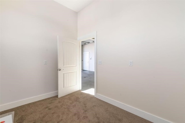 carpeted empty room with lofted ceiling and baseboards