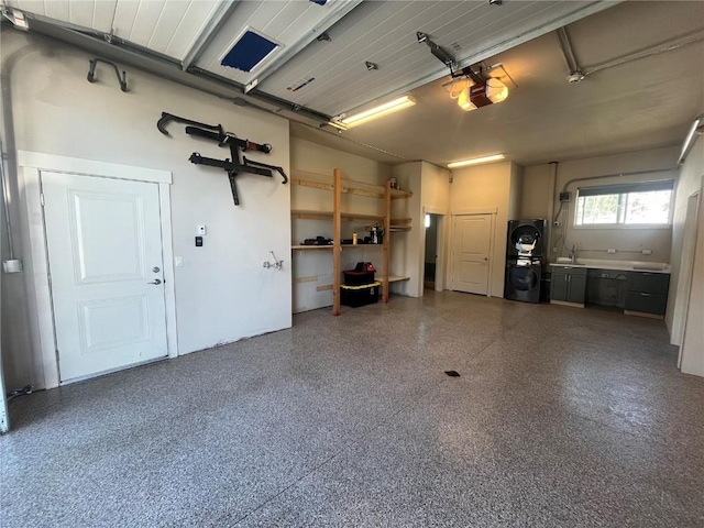 garage featuring a sink, a garage door opener, and stacked washer and dryer