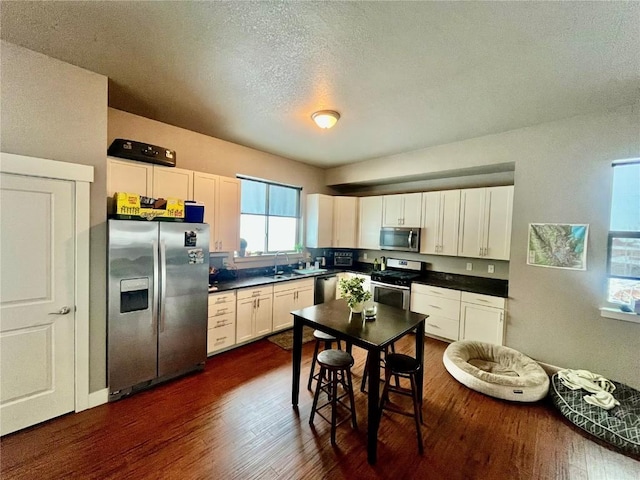 kitchen with dark wood-type flooring, white cabinets, and stainless steel appliances