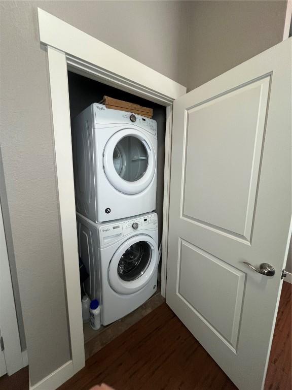 washroom with laundry area, stacked washing maching and dryer, and dark wood-style flooring