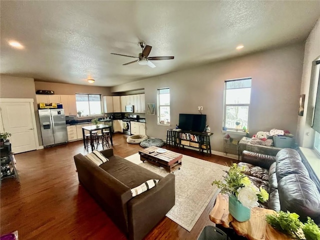 living area with plenty of natural light, dark wood-type flooring, and ceiling fan