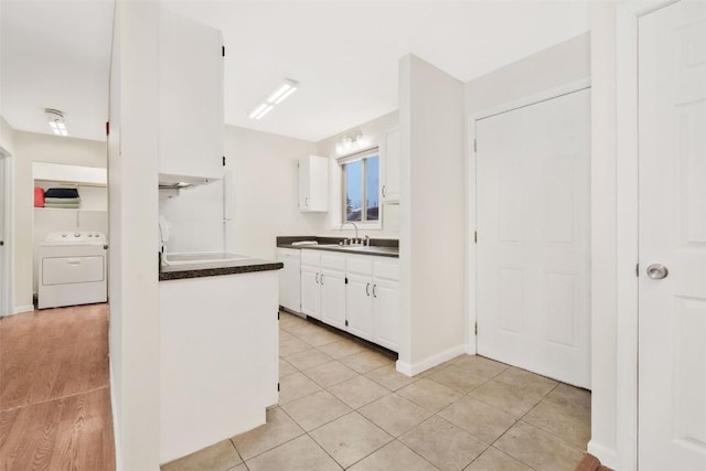 kitchen with washer / dryer, white cabinetry, sink, and light tile patterned floors