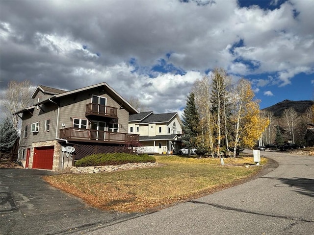 view of property exterior with a lawn, a wooden deck, a balcony, and a garage