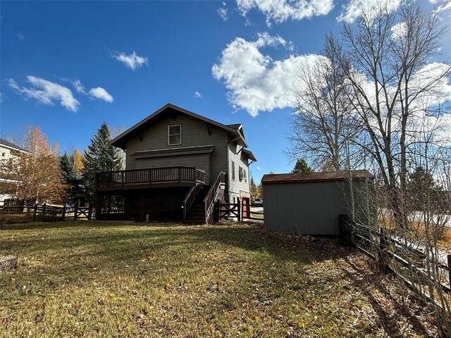 back of property featuring a storage shed, a deck, and a yard