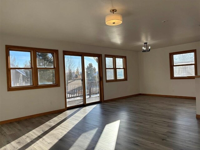 spare room with a notable chandelier and dark wood-type flooring