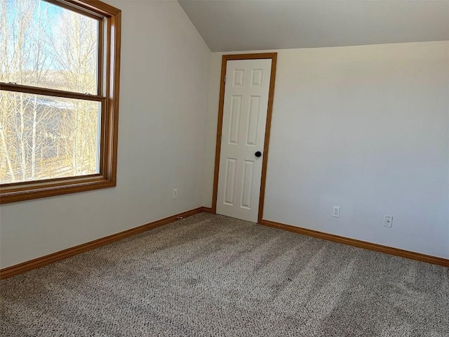 carpeted empty room featuring lofted ceiling