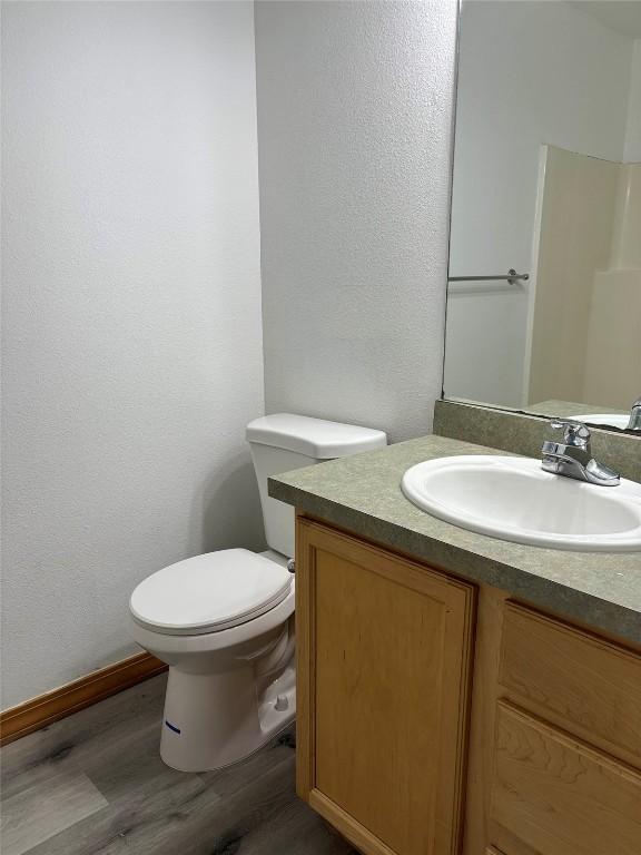 bathroom with wood-type flooring, vanity, toilet, and walk in shower