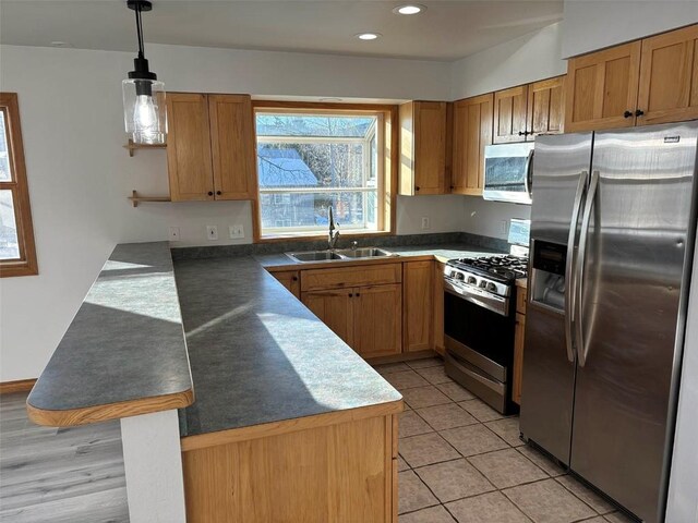 kitchen featuring kitchen peninsula, stainless steel appliances, sink, light tile patterned floors, and hanging light fixtures