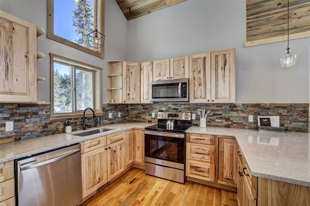 kitchen featuring light brown cabinetry, sink, high vaulted ceiling, hanging light fixtures, and appliances with stainless steel finishes