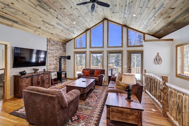 living room with high vaulted ceiling, a wood stove, wood ceiling, and light wood-type flooring