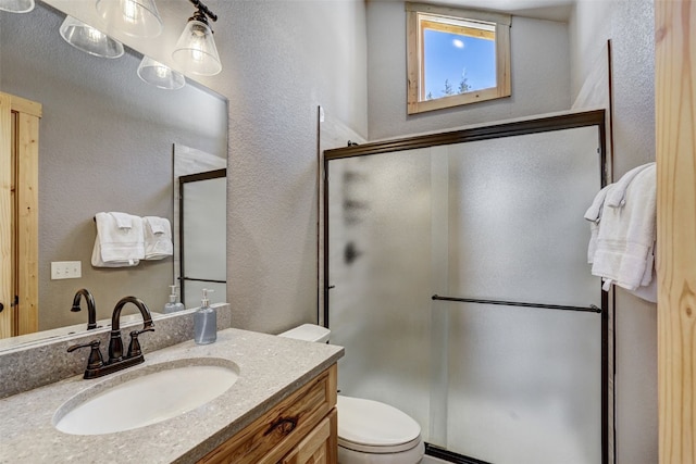 bathroom with vanity, toilet, and a shower with shower door