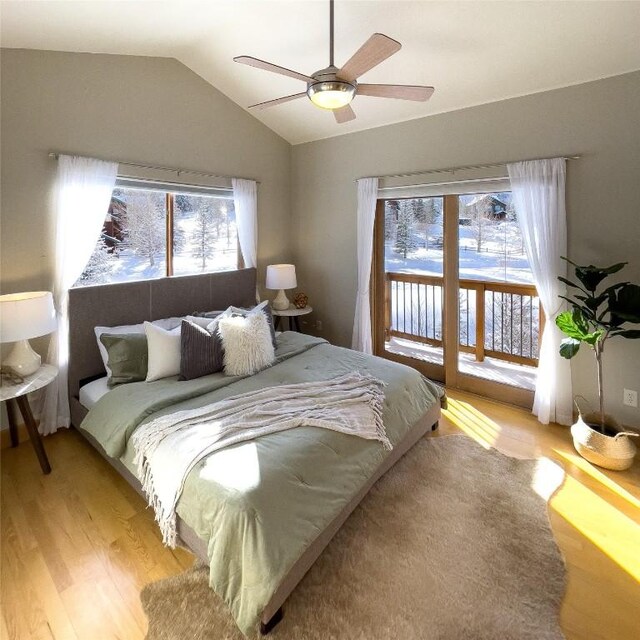 bedroom with light wood-type flooring, vaulted ceiling, multiple windows, and access to exterior