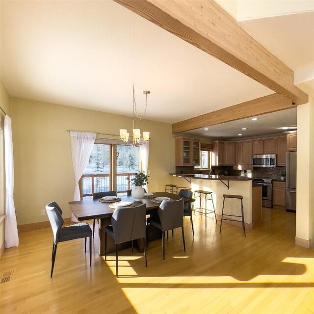 dining room featuring beam ceiling, light hardwood / wood-style floors, and a chandelier