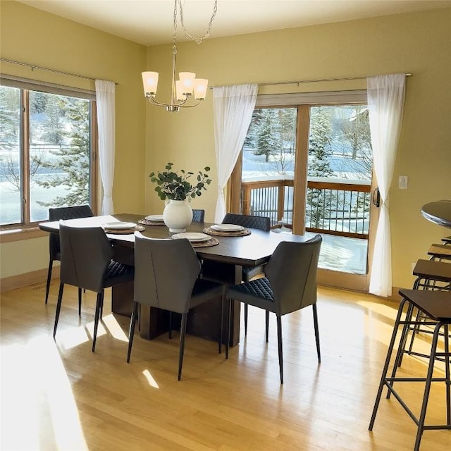 dining space featuring light hardwood / wood-style flooring, an inviting chandelier, and a wealth of natural light