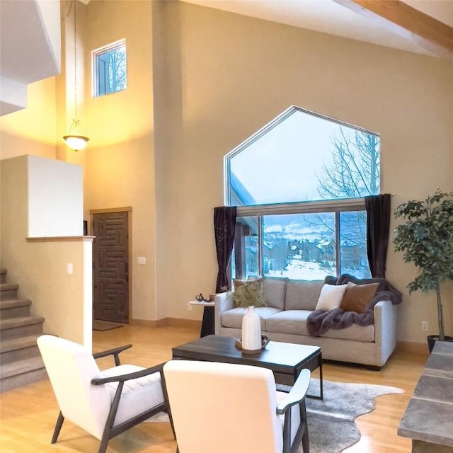 living room with light hardwood / wood-style floors, a wealth of natural light, and a towering ceiling