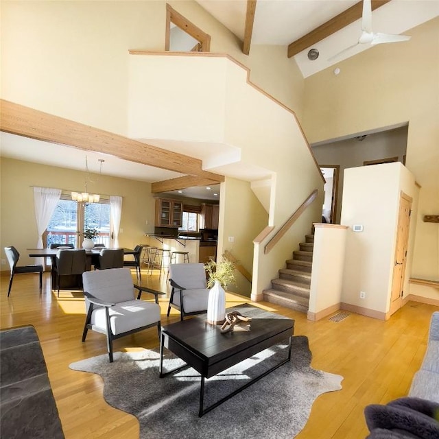 living room featuring hardwood / wood-style flooring, high vaulted ceiling, a chandelier, and beam ceiling