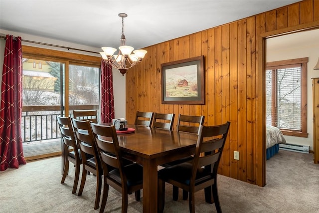 dining room with a notable chandelier, carpet flooring, a baseboard radiator, and wood walls