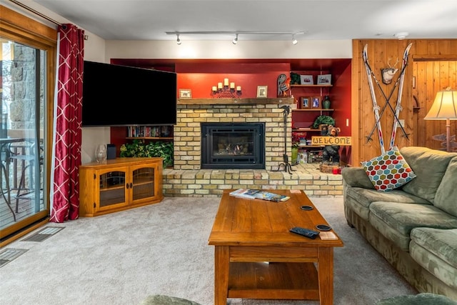 carpeted living room with wood walls and a fireplace