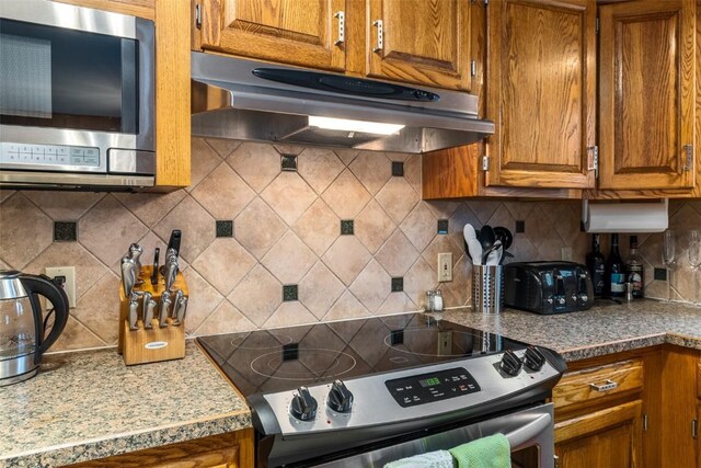 kitchen with decorative light fixtures, plenty of natural light, backsplash, stainless steel range with electric stovetop, and a breakfast bar area