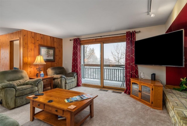 living room featuring track lighting, wooden walls, and light colored carpet