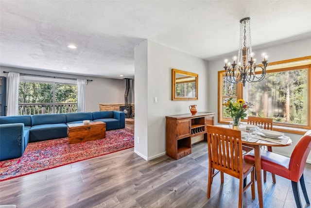 dining area featuring a notable chandelier, a textured ceiling, a wood stove, and wood finished floors