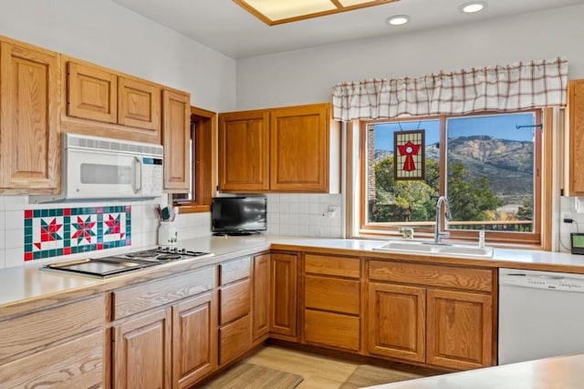 kitchen featuring sink, white appliances, light hardwood / wood-style floors, and decorative backsplash