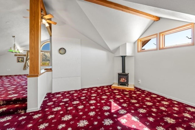 interior space with vaulted ceiling with beams, carpet, ceiling fan, and a wood stove