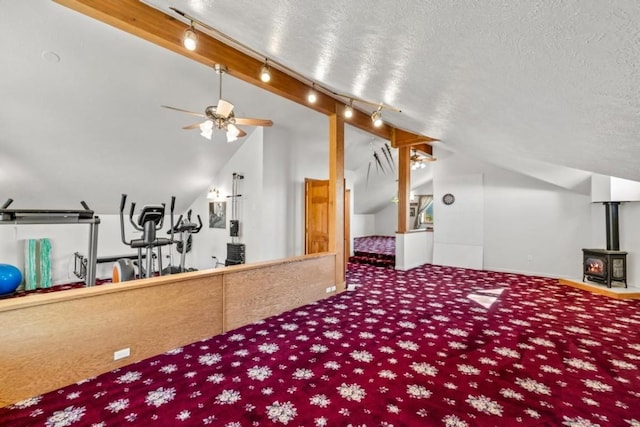 carpeted bedroom with lofted ceiling, rail lighting, a textured ceiling, and a wood stove