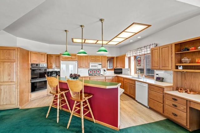 kitchen with a kitchen island, a breakfast bar, sink, hanging light fixtures, and white appliances