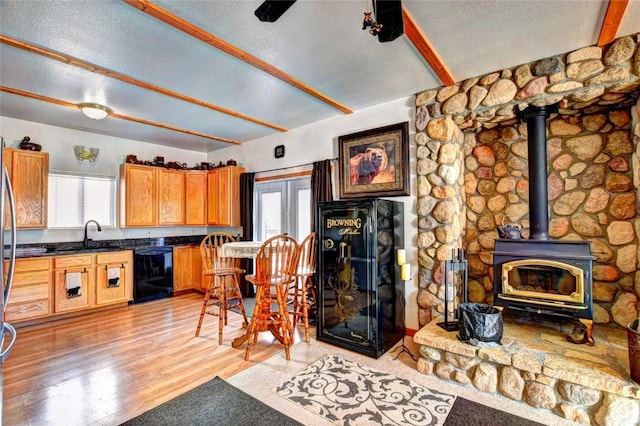 kitchen with a wood stove, a wealth of natural light, sink, and black dishwasher