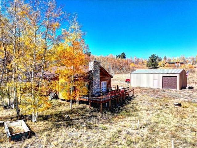 view of yard featuring a wooden deck, an outbuilding, and a garage