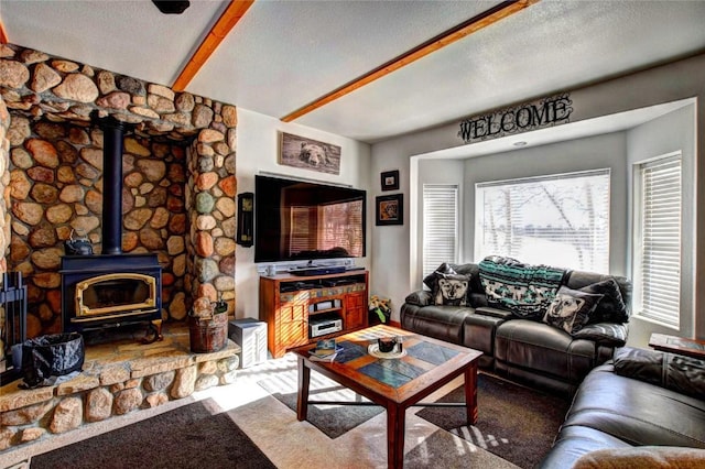 carpeted living room featuring a wood stove, beamed ceiling, and a textured ceiling