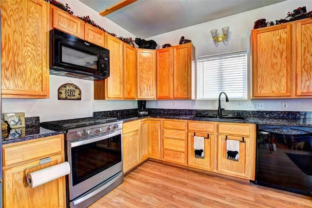 kitchen with dark stone countertops, sink, black appliances, and light hardwood / wood-style floors