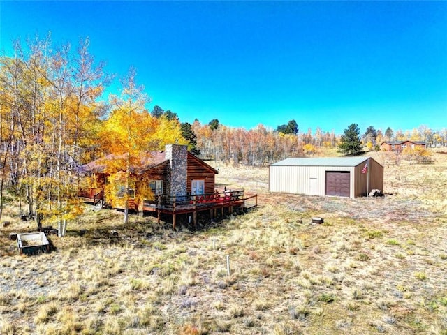 view of yard featuring a garage, a deck, and an outbuilding