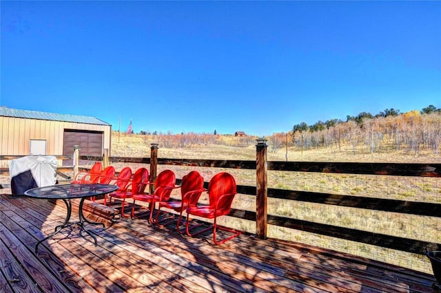 wooden terrace featuring a grill, an outbuilding, and a rural view