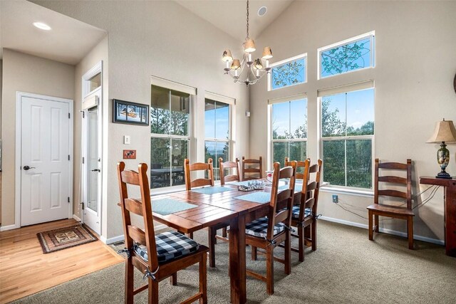 carpeted dining room with high vaulted ceiling and an inviting chandelier