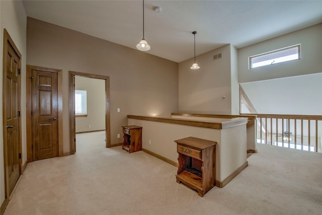 hallway with light carpet, high vaulted ceiling, baseboards, and visible vents